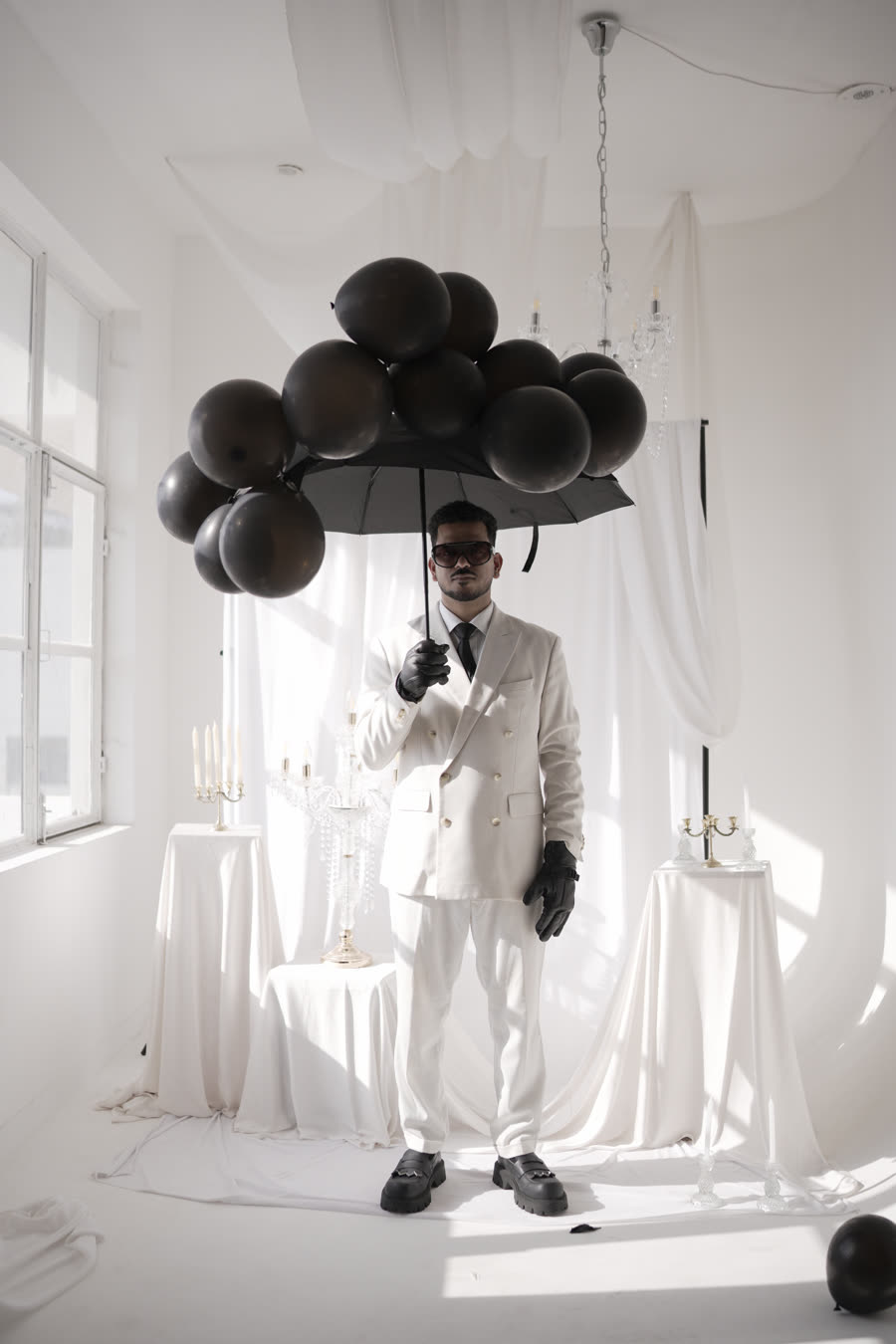 Semwal in a white suit under a canopy of black balloons